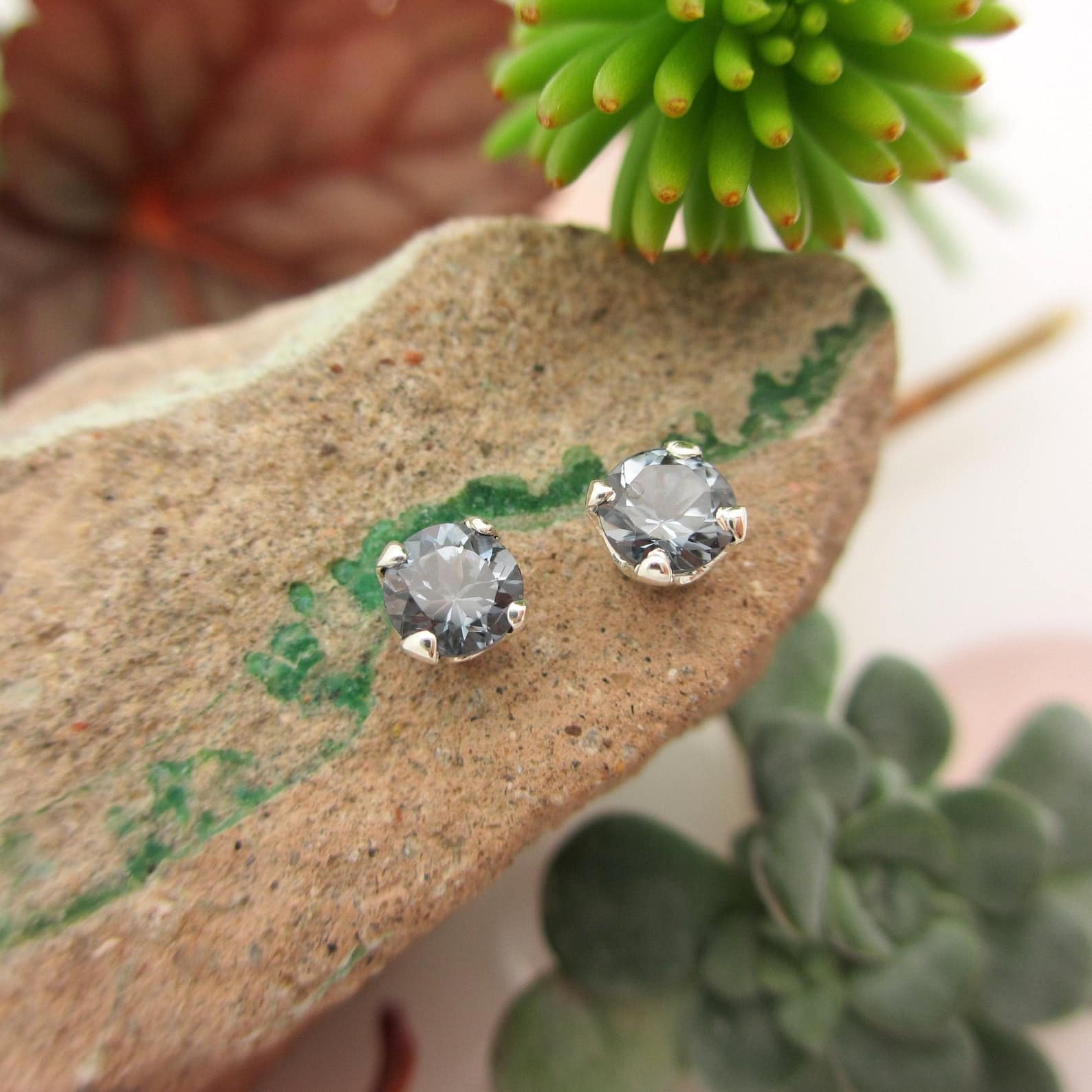 gray spinel earrings on top of the rock