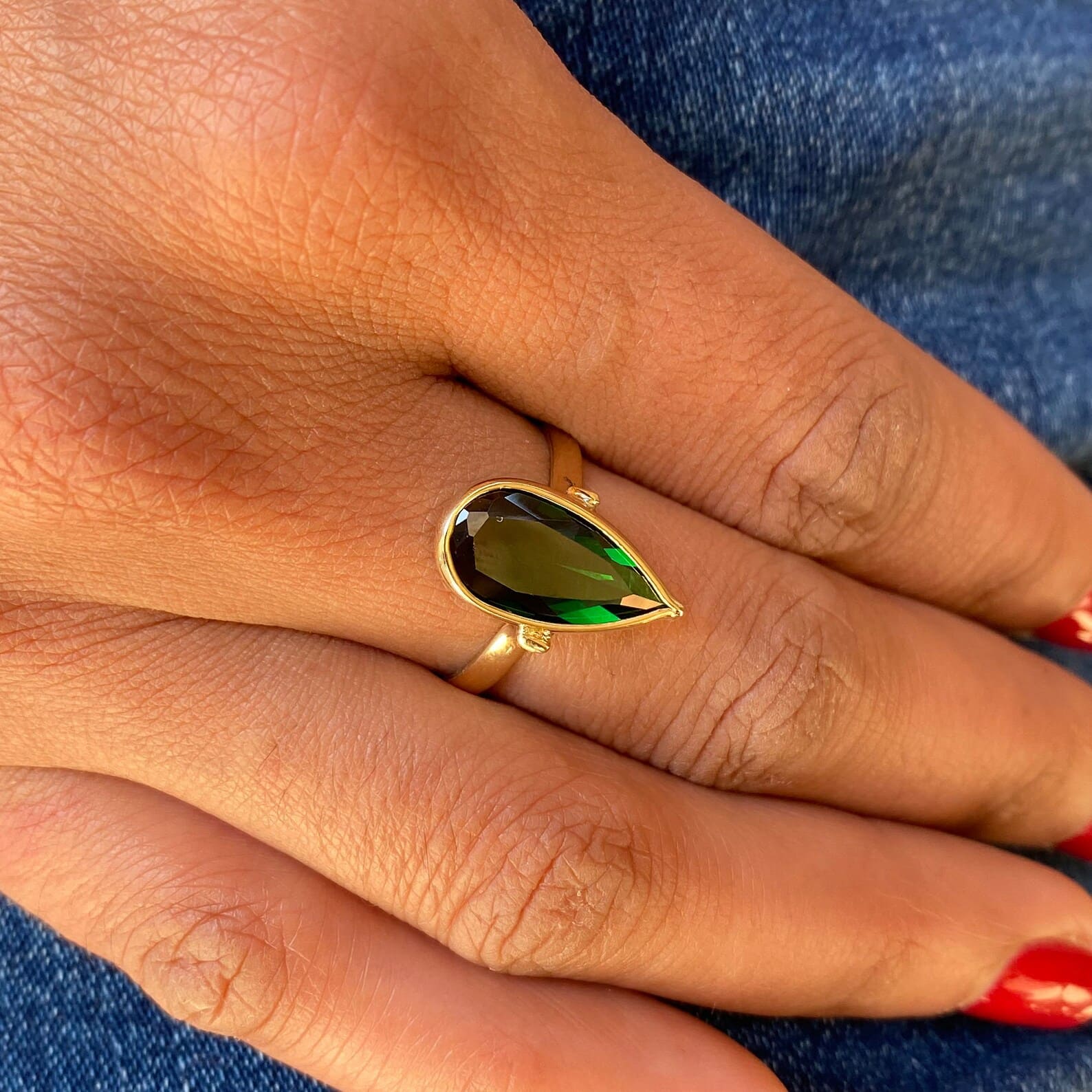 green spinel gold ring on the ring finger